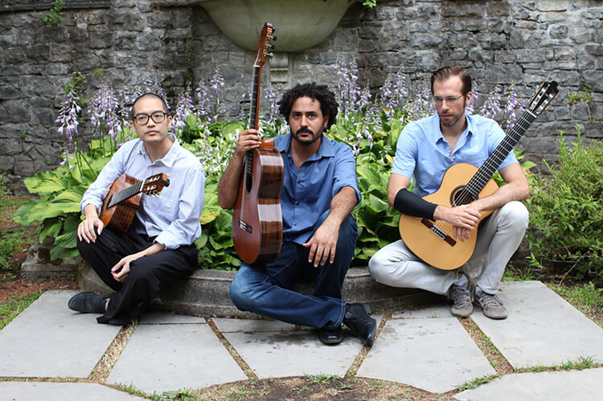 three men with guitars sitting on the ground